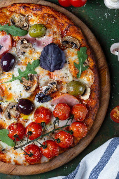 istock Delicious fresh pizza with ham, mushrooms and tomatoes 1186134827