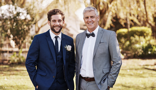 Cropped portrait of a handsome young bridegroom smiling while standing with his father on his wedding day