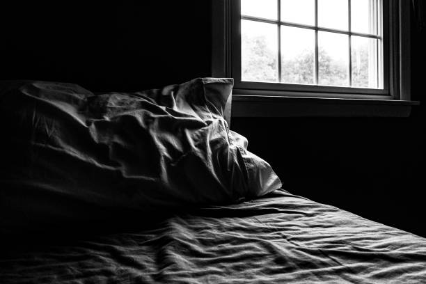 istock Dark Bedroom Sunlight Window Rumpled Bed and Pillow 1186135177