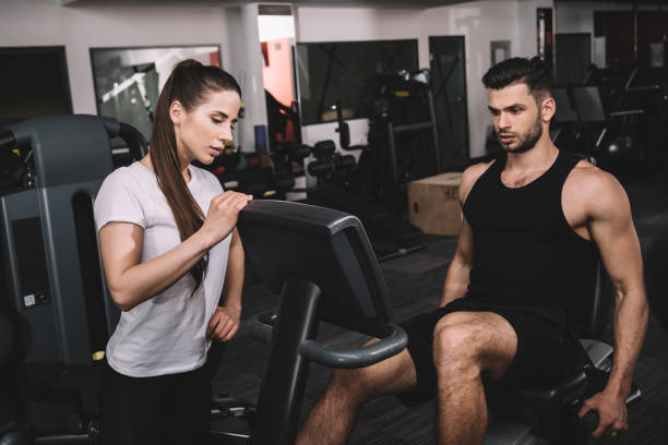 istock attractive trainer instructing handsome sportsman working out on recumbent elliptical trainer 1186137717