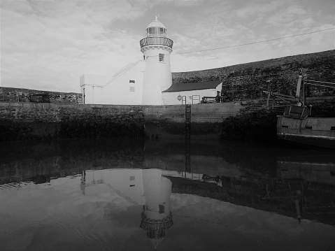 Black and white image of Balgriggan pier with lighthouse reflected in the sea.