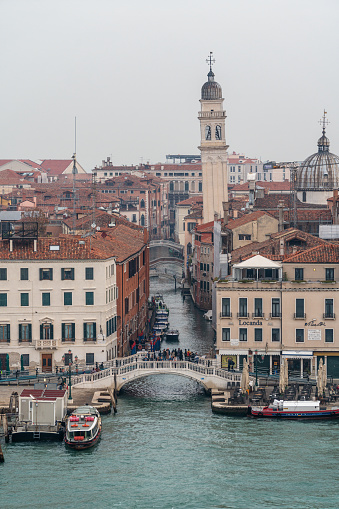 Venice, Italy - October 18, 2019: View from a cruise ship of Venice on an autumn sunrise. A bridge is located over the Rio dei Greci canal. At the edge of the canal is the leaning bell tower of the Chiesa di San Giorgio Dei Greci, a Greek orthodox church.
