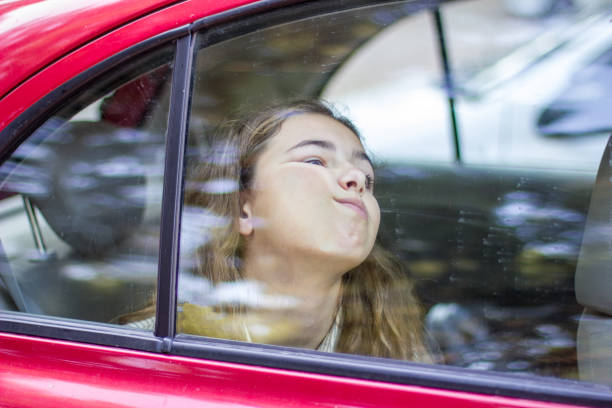 junges mädchen in einem auto täuscht herum und macht lustige gesichter am fenster - making a face child humor human face stock-fotos und bilder