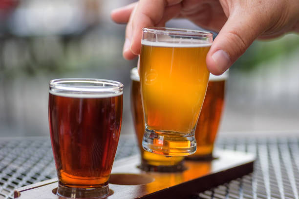 Sampling beer from a flight Tasting seasonal Beer Fest beer at a local craft brewery - man’s hand lifting glass, closeup mini wheat cereal stock pictures, royalty-free photos & images