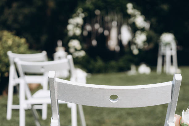 une place pour les invités à une cérémonie de mariage, chaises blanches décorées de fleurs. décorations de mariage. mise au point sélective, film et photo de grain - just married concepts ideas place setting photos et images de collection