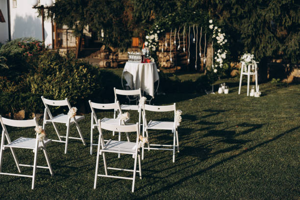 une place pour les invités à une cérémonie de mariage, chaises blanches décorées de fleurs. décorations de mariage. mise au point sélective, film et photo de grain - just married concepts ideas place setting photos et images de collection