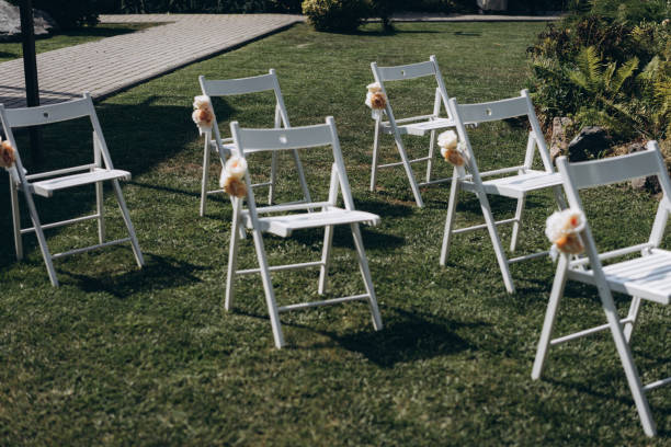 une place pour les invités à une cérémonie de mariage, chaises blanches décorées de fleurs. décorations de mariage. mise au point sélective, film et photo de grain - just married concepts ideas place setting photos et images de collection