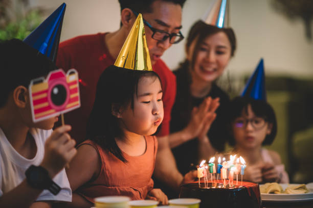 asian chinese Happy little girl blowing out candles on a birthday cake Happy little girl blowing out candles on a birthday cake birthday wishes for daughter stock pictures, royalty-free photos & images