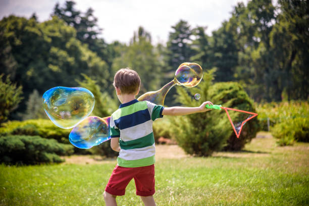 istock Little boy playing with his soap bubbles toy in the park. Child activity. Springtime concept 1186148164