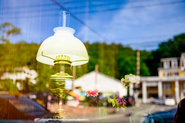 This is a photograph of an antique lamp on retail display in a small, rural town in upstate New York. Grass covered mountains and old fashioned buildings are reflected in the glass.