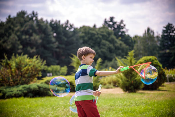 istock Little boy playing with his soap bubbles toy in the park. Child activity. Springtime concept 1186148359
