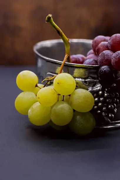 fresh grapes in a tin bowl decorated with grapes