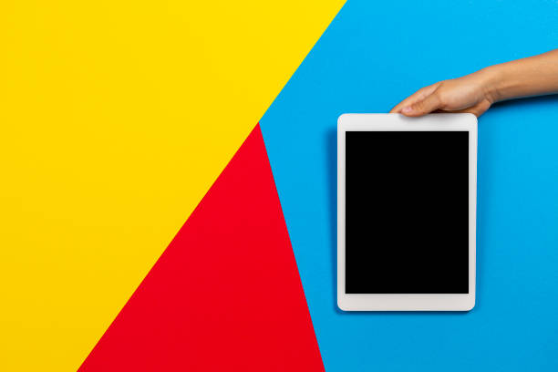 istock Kid hand with tablet computer on yellow, red and light blue background 1186156507