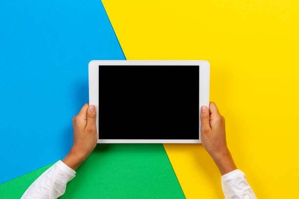 istock Kid hands with tablet computer on yellow, blue and green background 1186156717