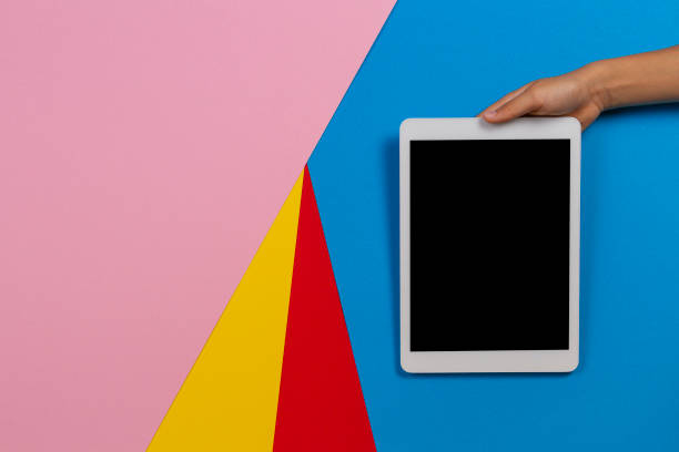 istock Kid hand with tablet computer on pink, light blue, yellow and red background 1186156792