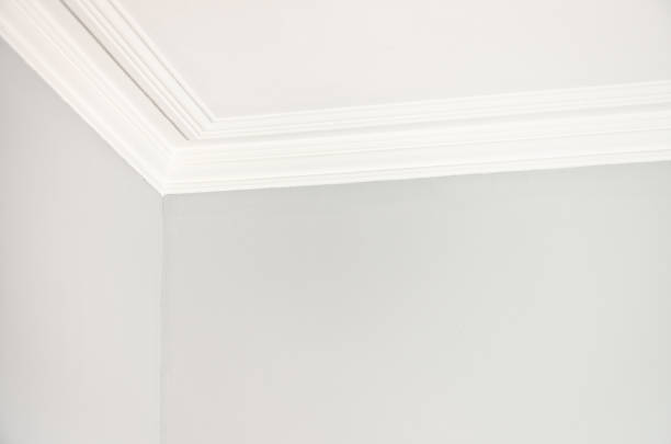 Interior walls and ceiling Close-up of the corner of a room meeting the ceiling with a simple plaster cornice. architectural cornice stock pictures, royalty-free photos & images