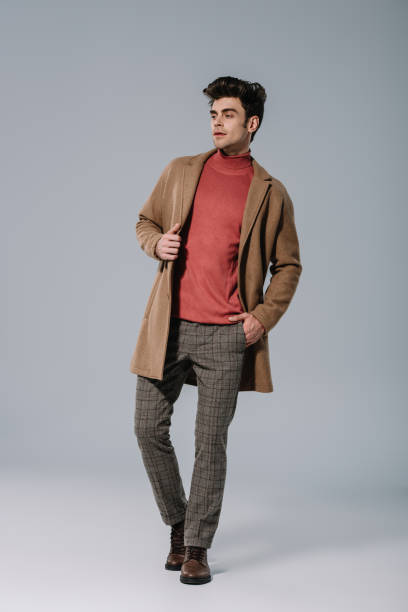 istock fashionable young man posing in beige coat on grey 1186159203