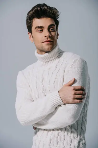 Photo of handsome man posing in knitted sweater, isolated on grey