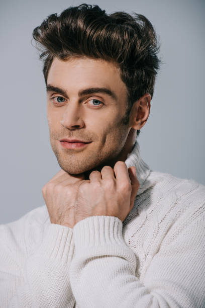istock happy stylish man posing in white knitted sweater, isolated on grey 1186159232