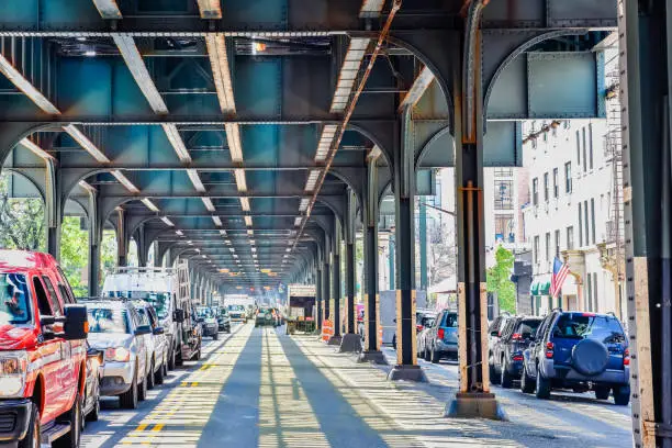 Photo of Bottom view of Elevated train track nyc. Traffic waiting in road in a sunny day. Travel and traffic concepts. Bronx, NYC, USA