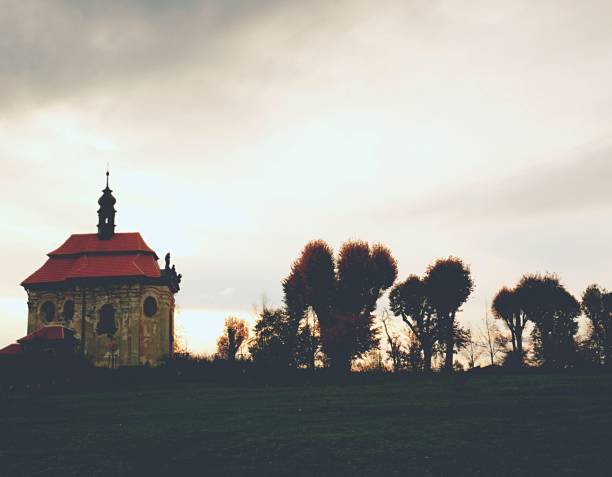 istock Chapel on hill with old lime trees alley. Dark meadows 1186160699