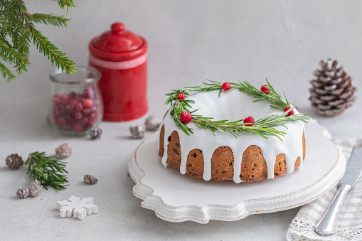 Traditional homemade Christmas fruit cake on the concrete background with a copyspace, decorated by cranberries and rosemary