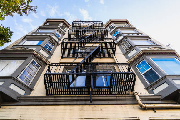 vista exterior del edificio residencial multifamiliar; viejas escaleras de escape de fuego metálico que cuelgan en el lado del edificio; berkeley, área de la bahía de san francisco - multi story building fotografías e imágenes de stock