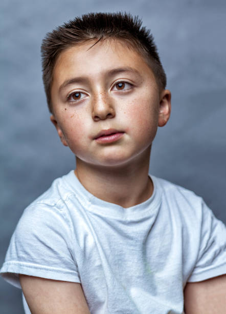 raza mixta niño asiático caucásico con pelo plano marrón en camiseta blanca mirando a la luz como un icono santo religioso - enzo fotografías e imágenes de stock