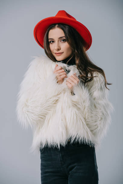 istock beautiful elegant model posing in white fur coat and red hat, isolated on grey 1186171912