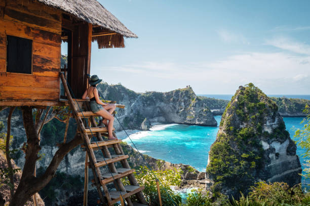 бали, индонезия, путешественник на tree house на алмазном пляже на острове нуса пенида - бали стоковые фото и изображения