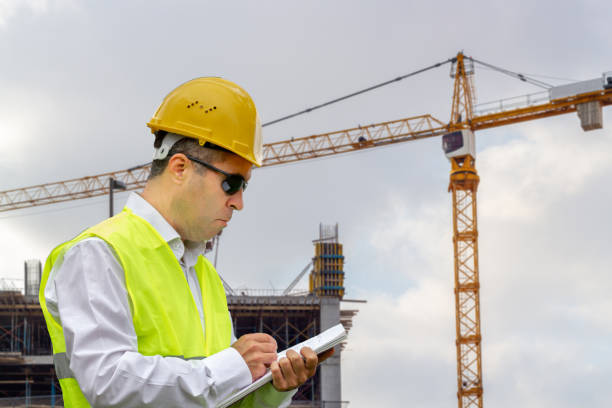 istock Construction worker man with safety helmet and vest works at construction site. Concept of people working in industrial field 1186177559