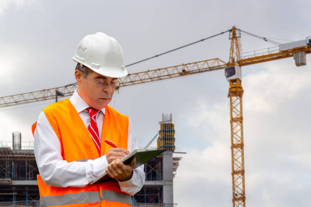 istock Construction engineer man in shirt and tie with safety helmet and vest works at construction site. Concept of people working in industrial field 1186177561
