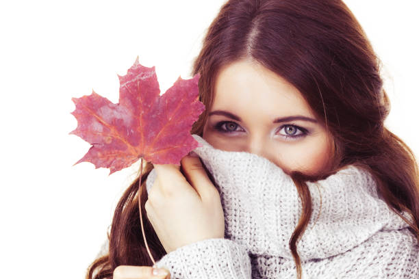 istock Woman with maple leaf hiding her face in sweater 1186178465