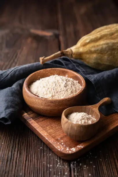 Organic baobab powder in a wooden bowl on rustic background, healthy sport nutrition rich in vitamins and minerals