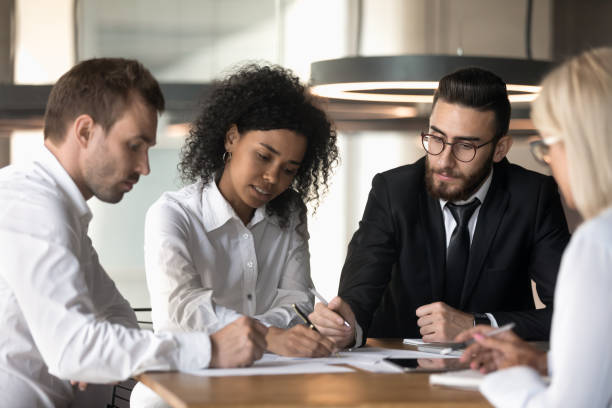 istock Multiracial team sitting reviewing documents financial stats at group meeting 1186185261