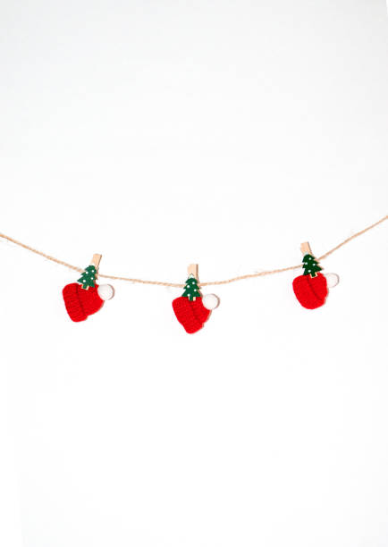 istock Christmas New Year composition. Garland from tiny red caps and christmas tree pins on white background 1186186069