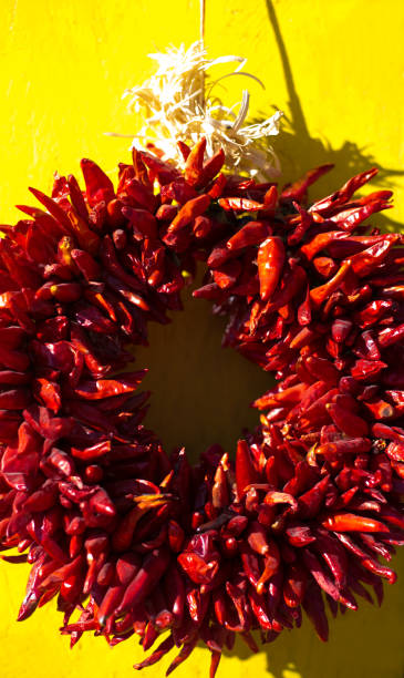 santa fe stil: weihnachten rot ristra kranz, gelben hintergrund - wreath chili pepper pepper ristra stock-fotos und bilder