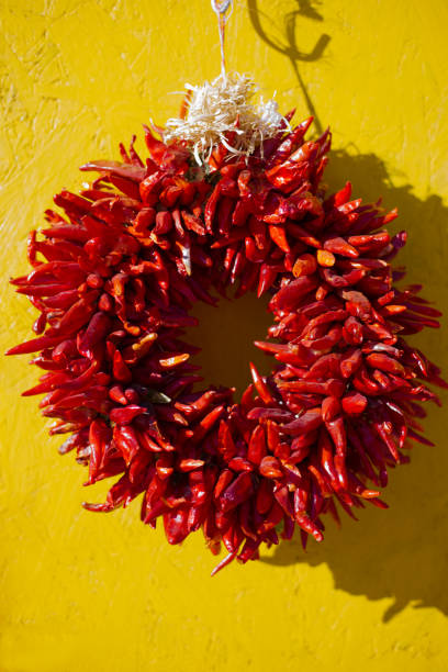 santa fe stil: weihnachten rot ristra kranz, gelben hintergrund - wreath chili pepper pepper ristra stock-fotos und bilder
