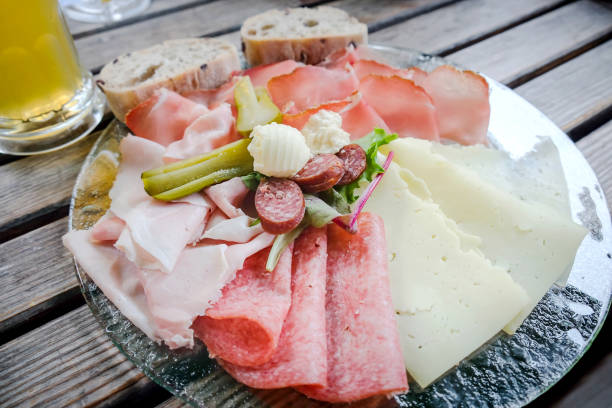 Close up shot of Italian tapas charcuterie with chorizo, cured ham, salami, cheese, butter ,pickle , bread and glass of beer