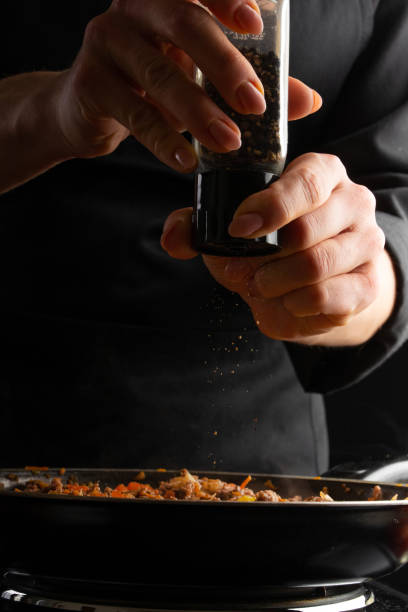 istock Chef cooks, fries in a pan. Cooking dishes. Peppers. Freezing in motion. Vertical frame. 1186199630