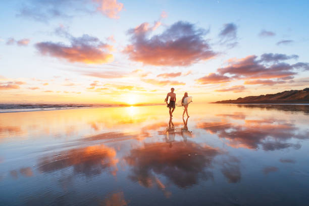 couples de surfeur s'en arrière après une longue journée à la plage. - north island new zealand photos et images de collection