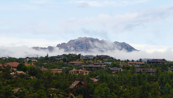 Granite Mountain clothed in low misty clouds as morning comes to Northern Arizona.