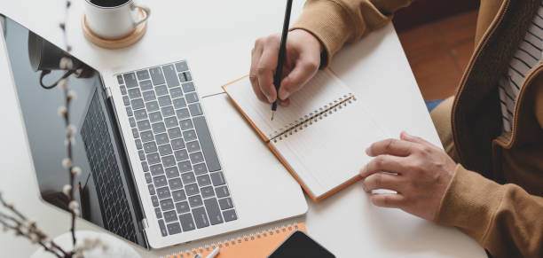 istock Cropped shot of male freelancer working on his project while writing his ideas on notebook 1186211355