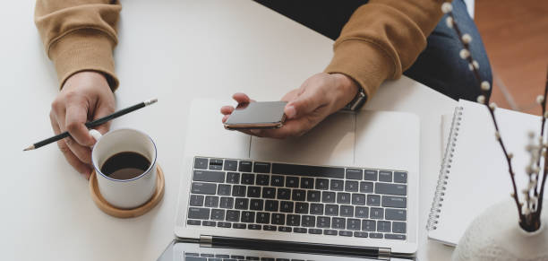 istock Cropped shot of young man working while looking at smartphone and drinking coffee 1186211394