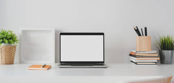 istock Minimal office room with open blank screen laptop computer and mock up frame 1186211403