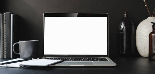 istock Open blank screen laptop computer in dark modern office room with office supplies 1186211423