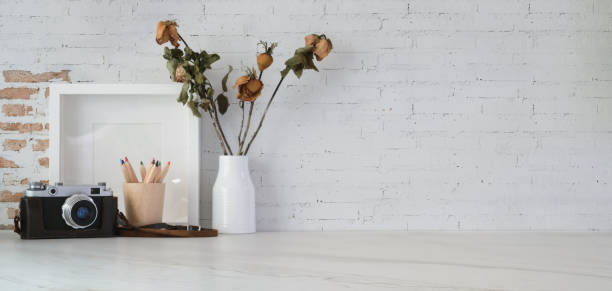 Minimal workplace with mock up frame, camera and office supplies on white table background with copy space