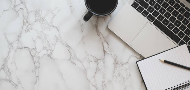 istock Top view of stylish workspace with laptop computer and notebook with coffee cup on marble table 1186212017