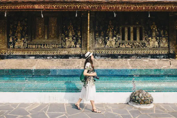 Photo of Portrait of young Asian tourist visiting Wat Xieng Thong an iconic temple in Luang Prabang, the UNESCO world heritage town in north central of Laos.