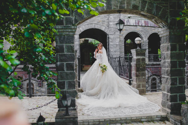 Young beautiful bride in luxury dress with a long train posing in country hotel stock photo